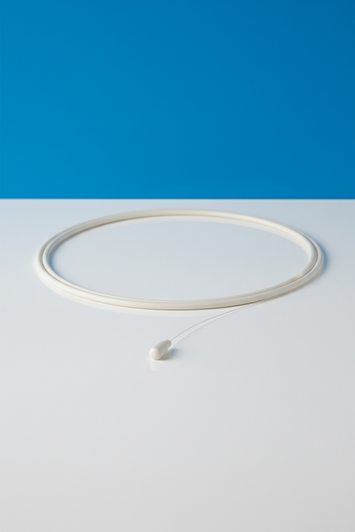 16-wire SS braid micro catheter coiled on white acrylic surface with royal blue background, distal tip visible